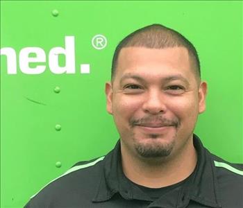 Man in black shirt in front of green background