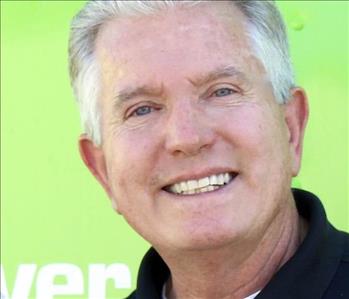 White male in black shirt in front of green background