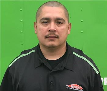 Man in black shirt in front of green background