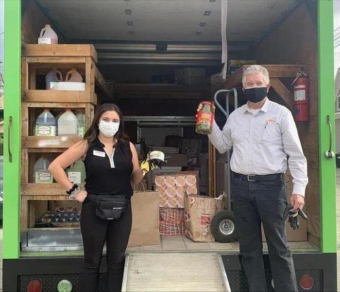 Woman and Man holding food in front of a green truck